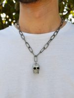 Colar corrente larga de metal com caveira pendente. Este colar é curto e possui fecho mesquetão com terminal de corrente ajustável. 